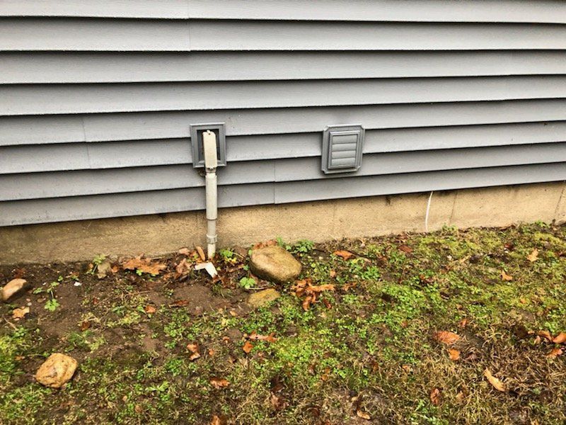 A pipe is connected to the side of a house.