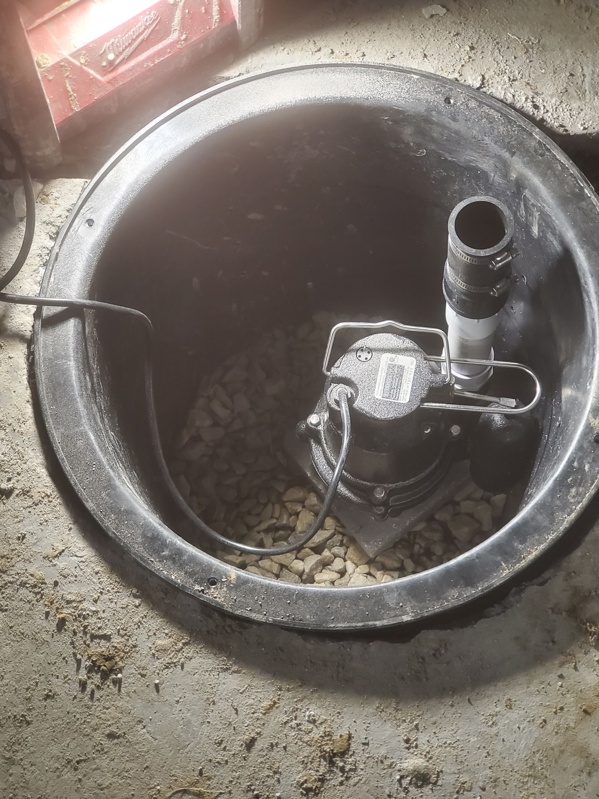 A sump pump is sitting in a hole in the ground.