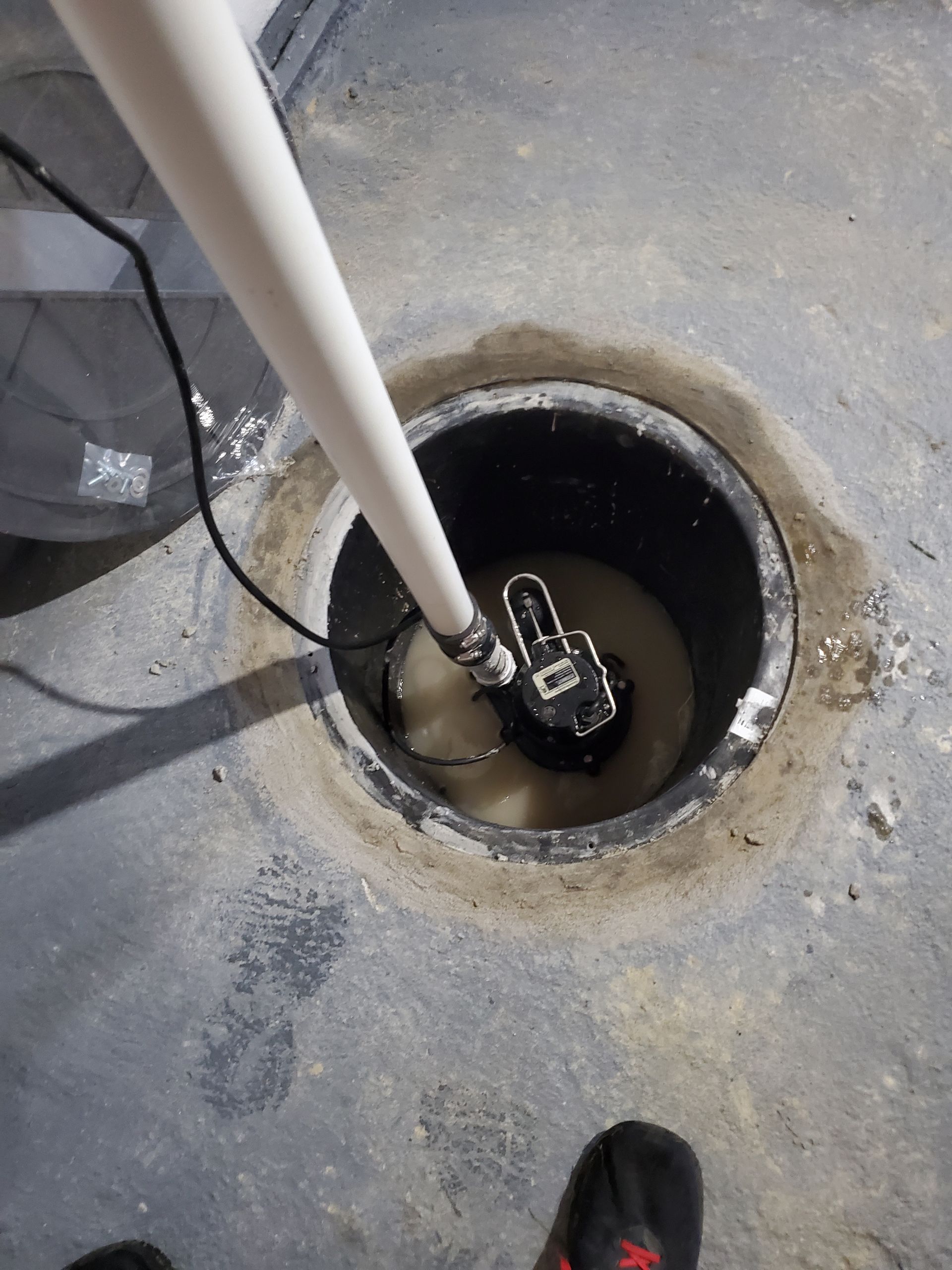 A person is standing in a hole with a pump in it.