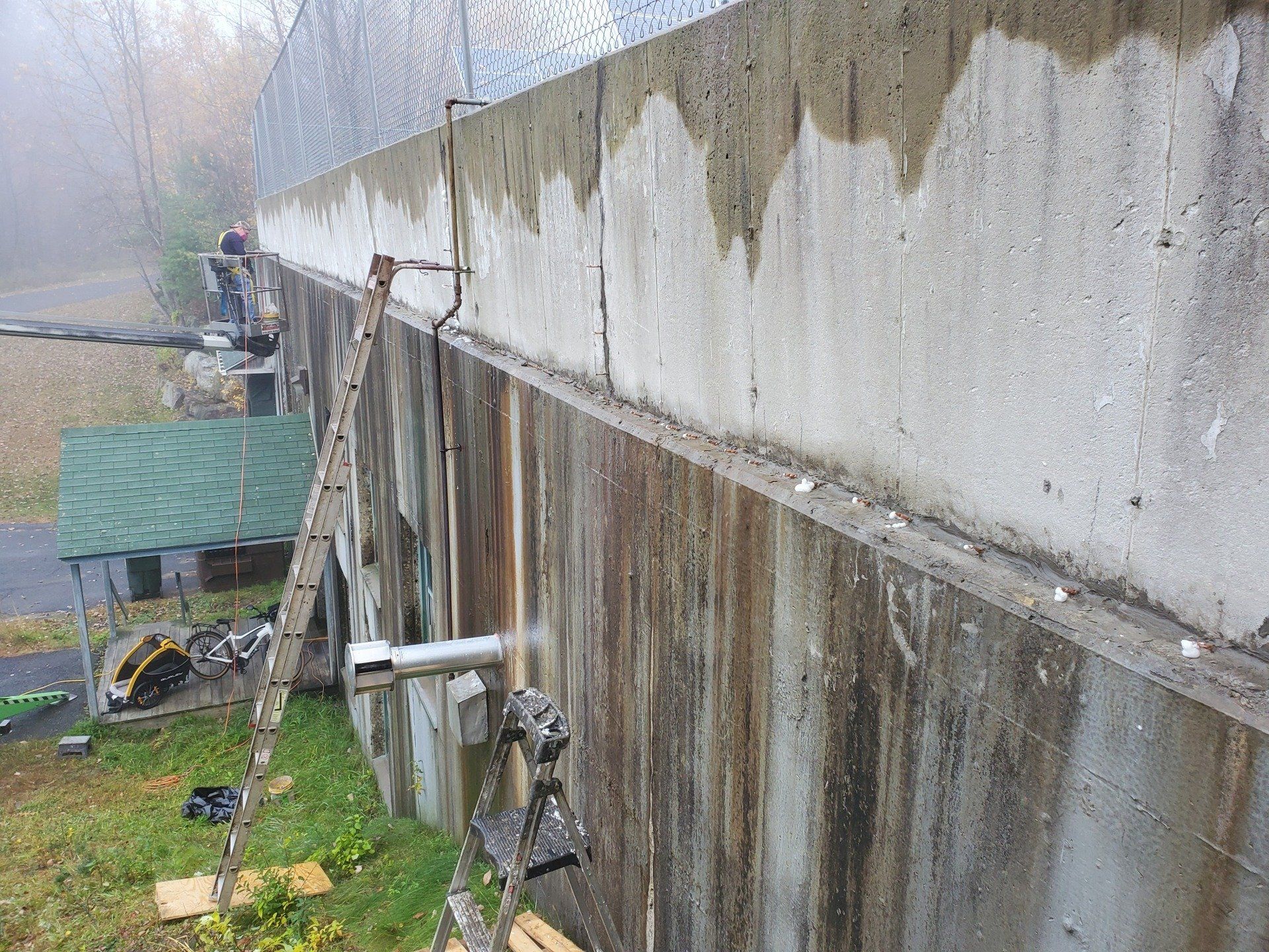 A ladder is sitting on the side of a concrete wall.