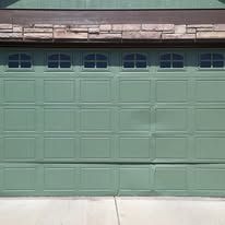 Green garage door with small windows under a brown roof