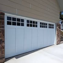 Light blue garage door with small window panels on a house exterior