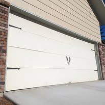 White double garage door with black handles on a house exterior