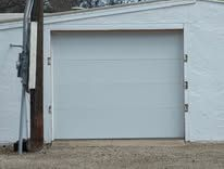 White garage door on a white building exterior with a utility pole beside it