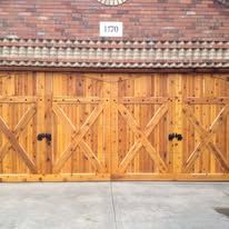 Wooden garage doors with diagonal braces beneath a brick wall and house number 170