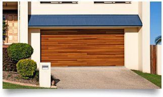 Modern house exterior with a wood garage door, blue awning, and paved driveway