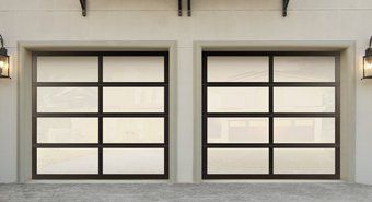 Two modern garage doors with black trim on a beige exterior wall
