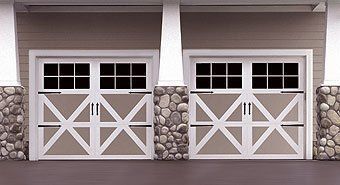 Two white garage doors with stone pillars and window panes on a house exterior