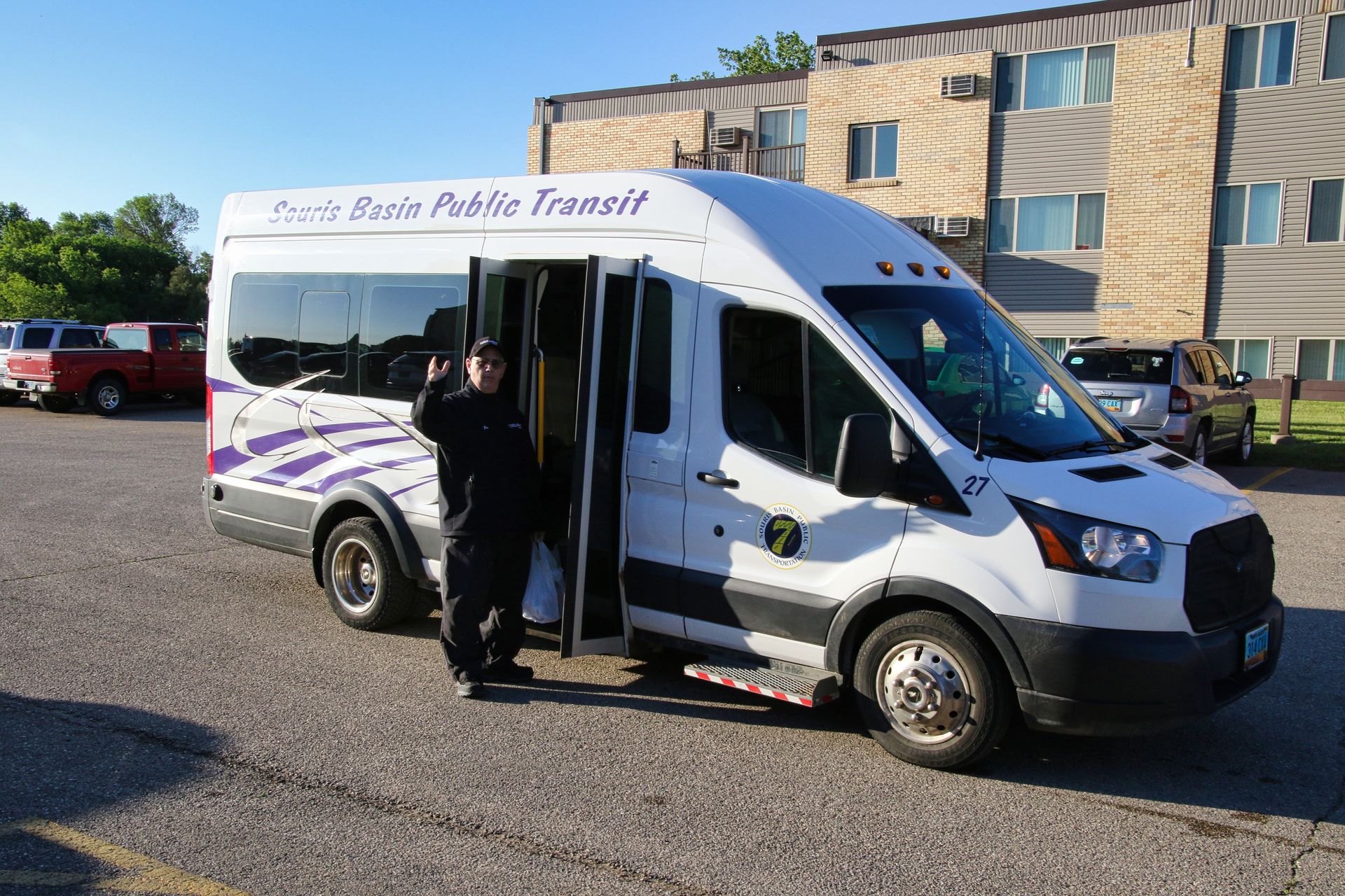 A white public transit van is parked in a parking lot