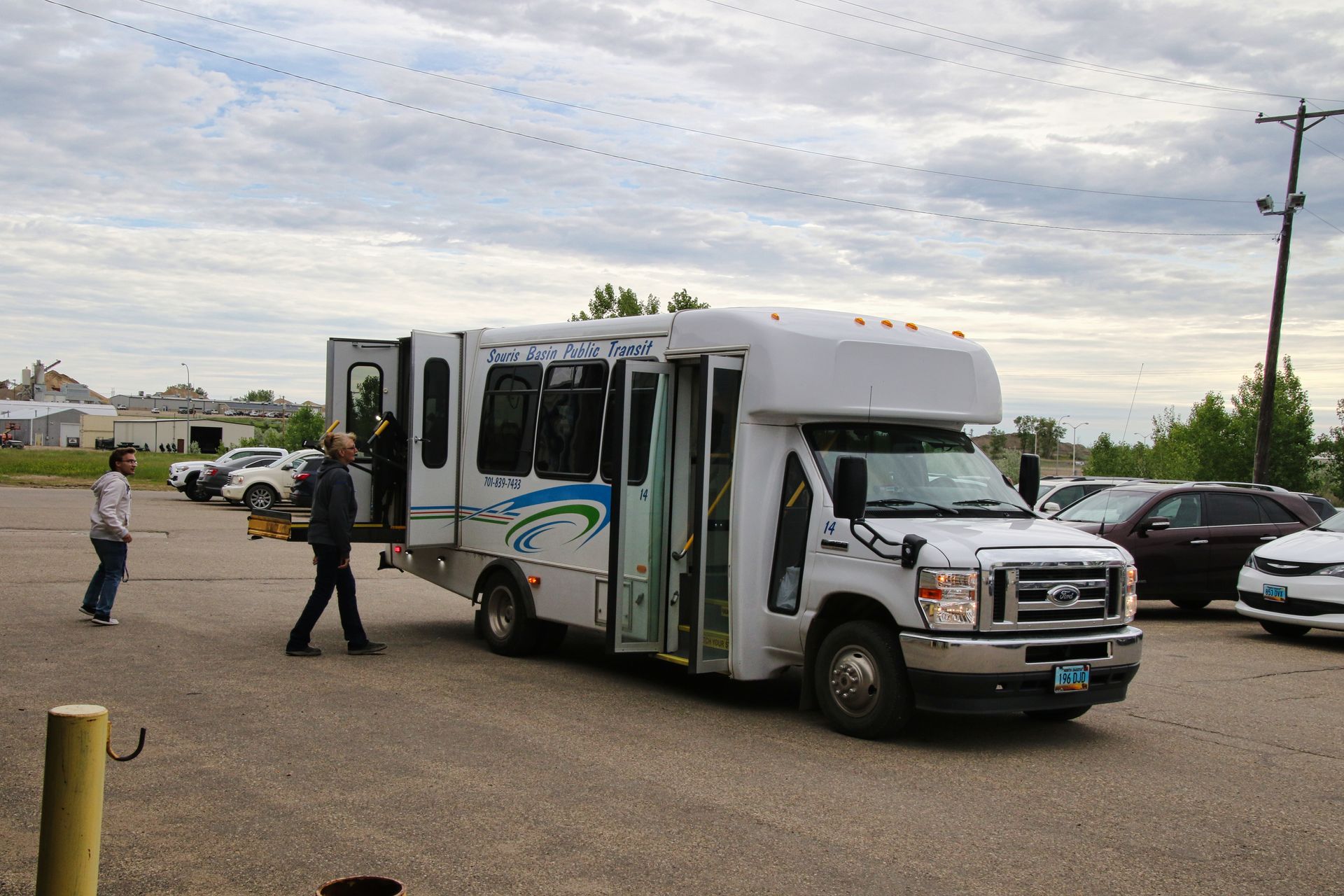 A white bus with the doors open is parked in a parking lot.