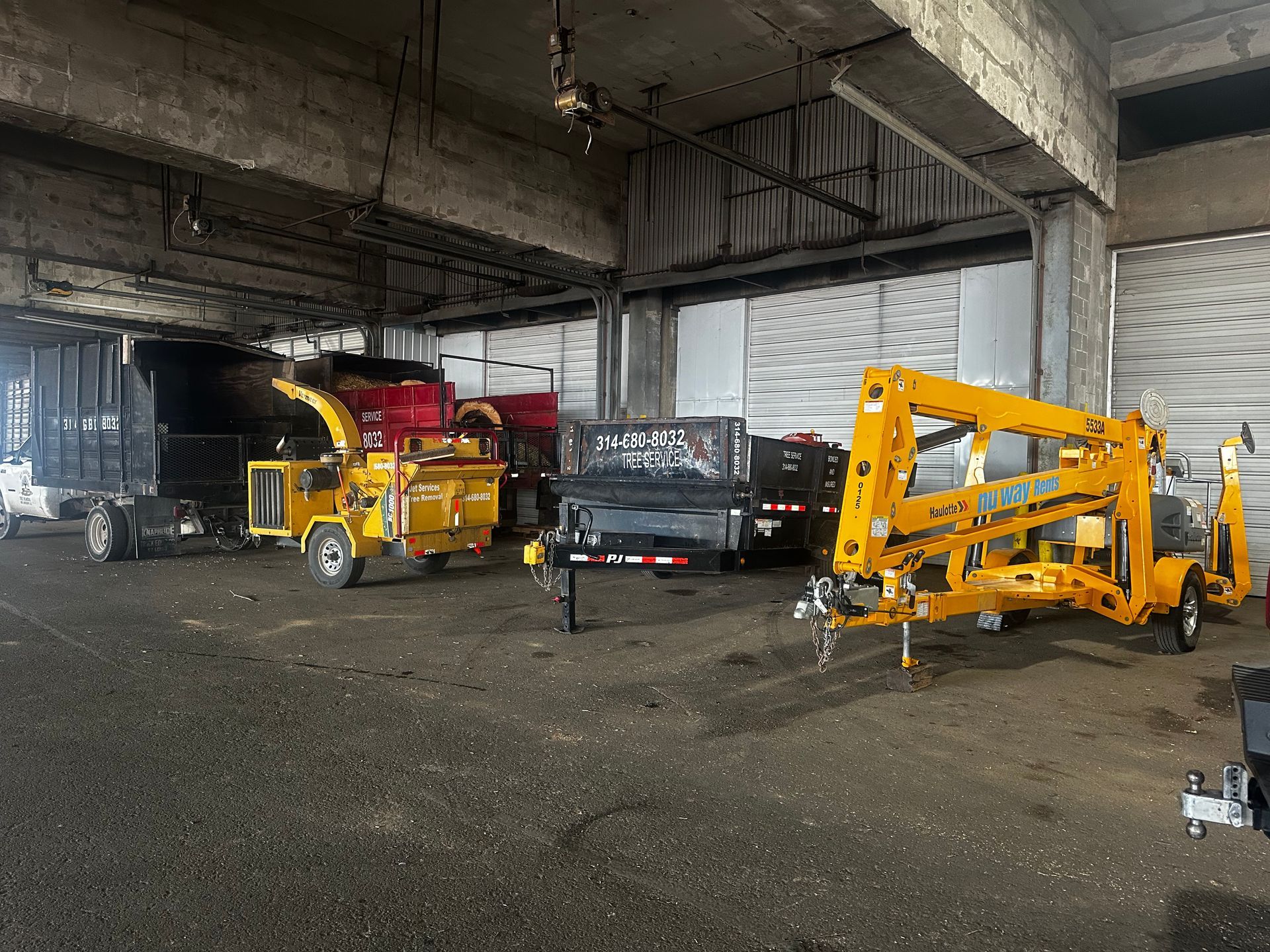 Yellow construction vehicles in a dim warehouse-like space with gravel on the floor.