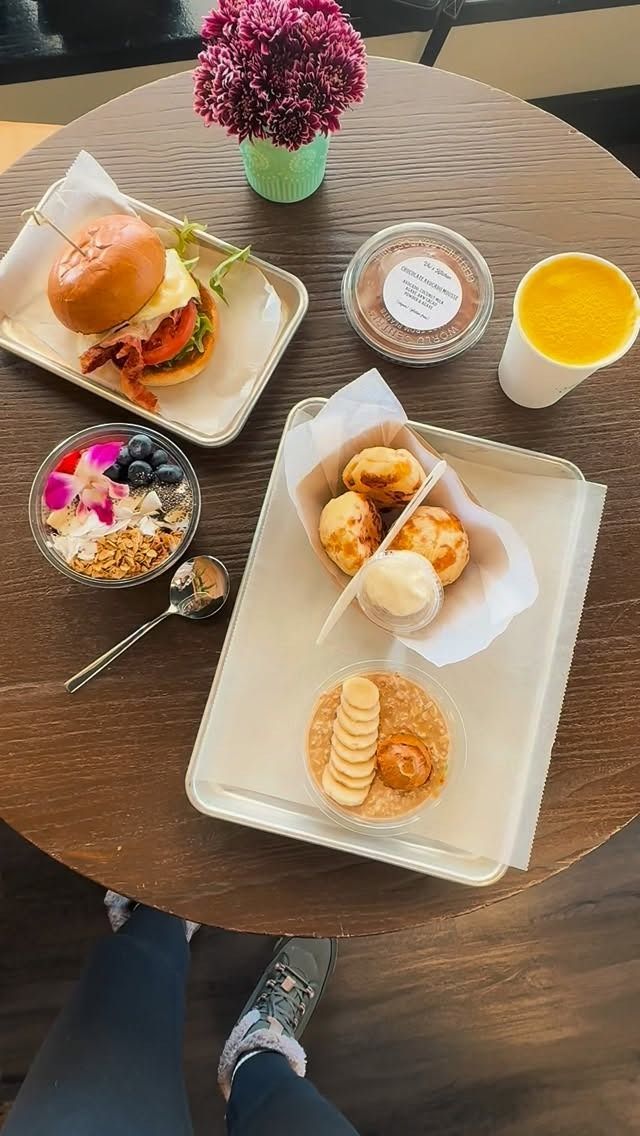 Overhead shot of a table with a burger, bowls of food, and a drink, likely at a cafe.