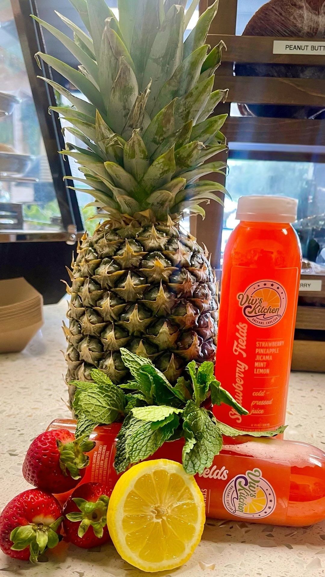 Pineapple, strawberries, mint, and lemon next to a bottle of strawberry-infused juice.