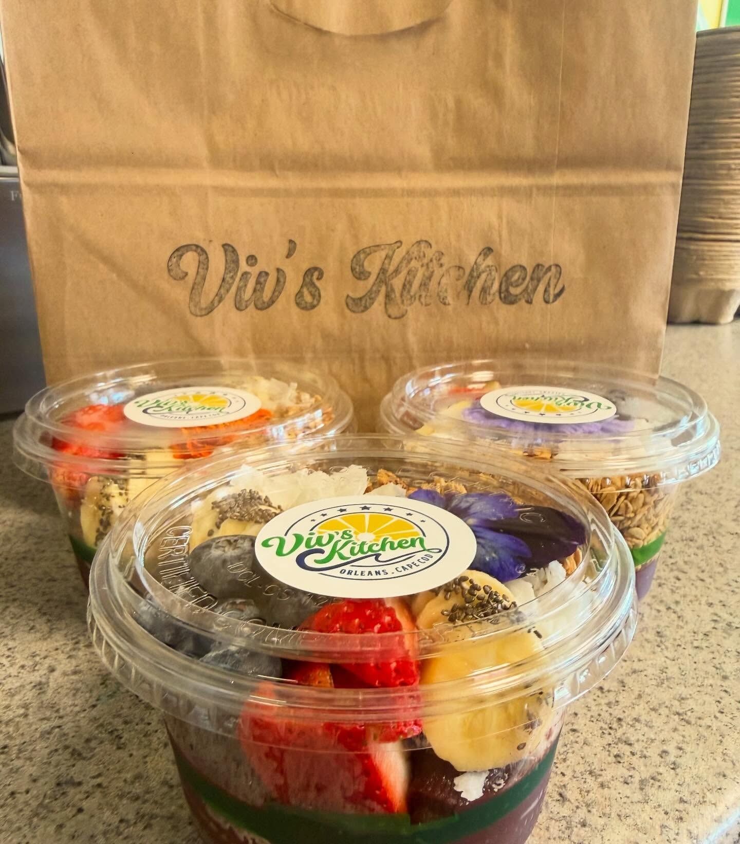 Three clear food cups with colorful fruit and dessert on a brown paper bag labeled Viv’s Kitchen.