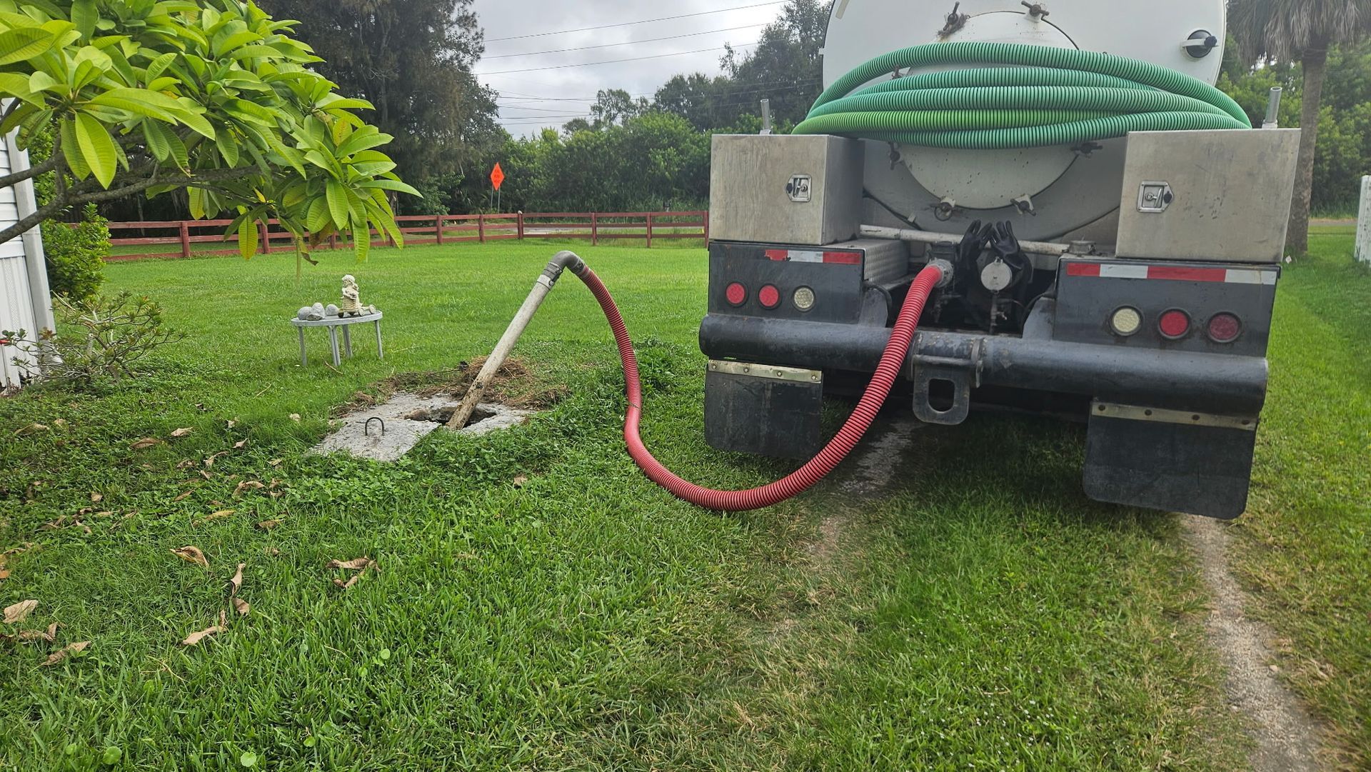Red tanker truck with a silver tank, parked outdoors on a sunny day.