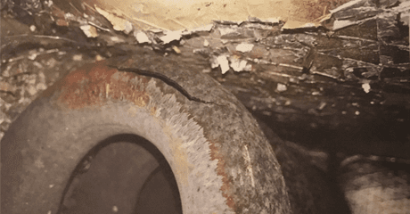 Close-up of a cracked, weathered, round structure with peeling white debris on the ceiling.
