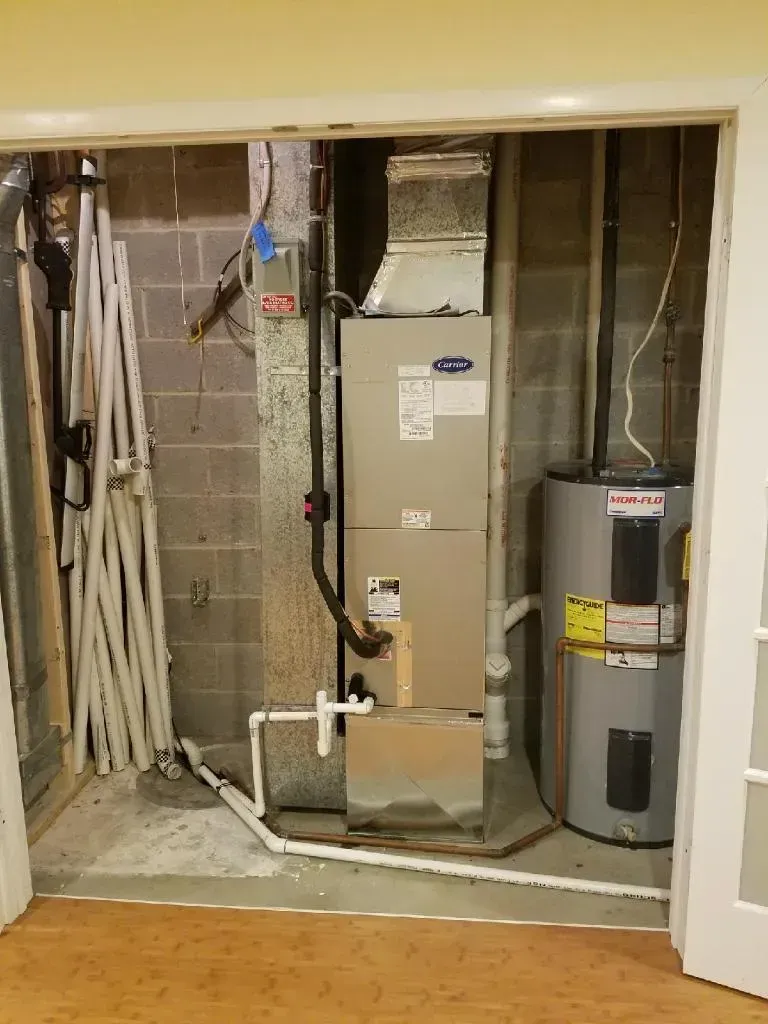 Furnace and hot water heater in a utility closet with concrete block walls.