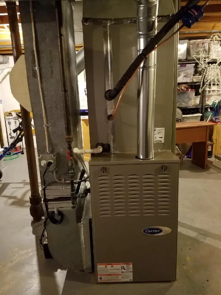 Gas furnace with metal vent pipes in a basement.