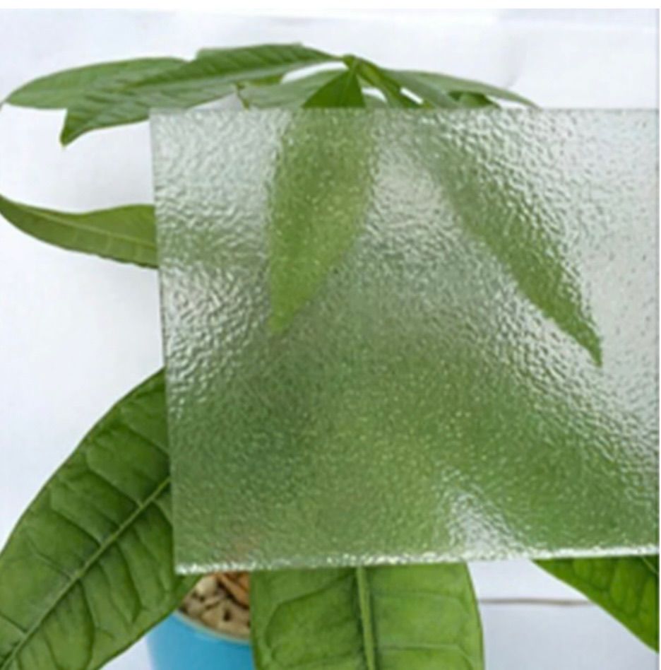 Textured clear glass sheet partially covering green plant leaves.