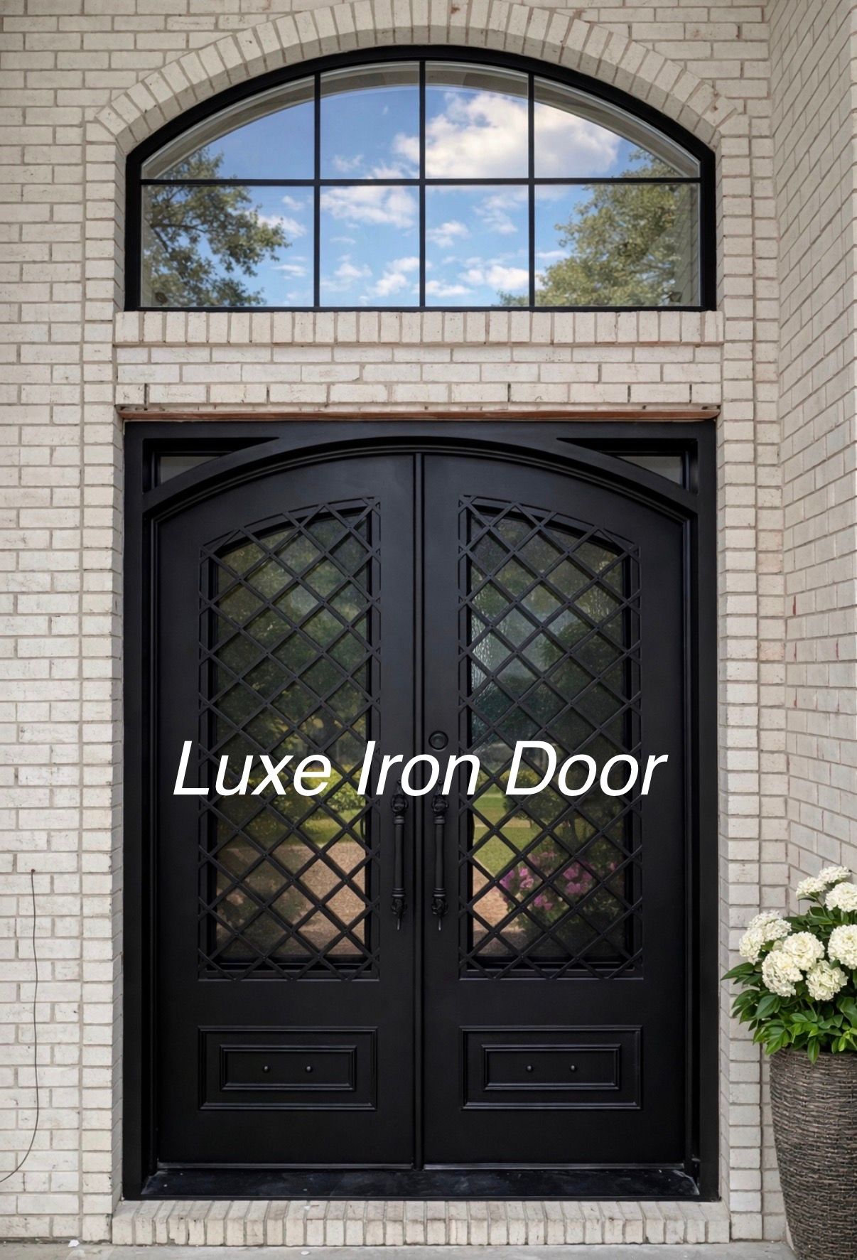 Double black iron door with a glass lattice pattern, topped by an arched transom window in a light brick exterior wall.