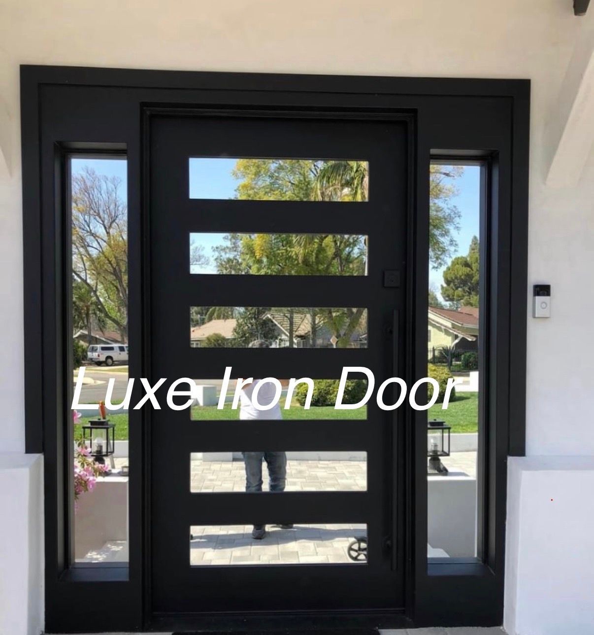 A black modern iron front door with six horizontal glass panels, flanked by two full-length vertical side windows.