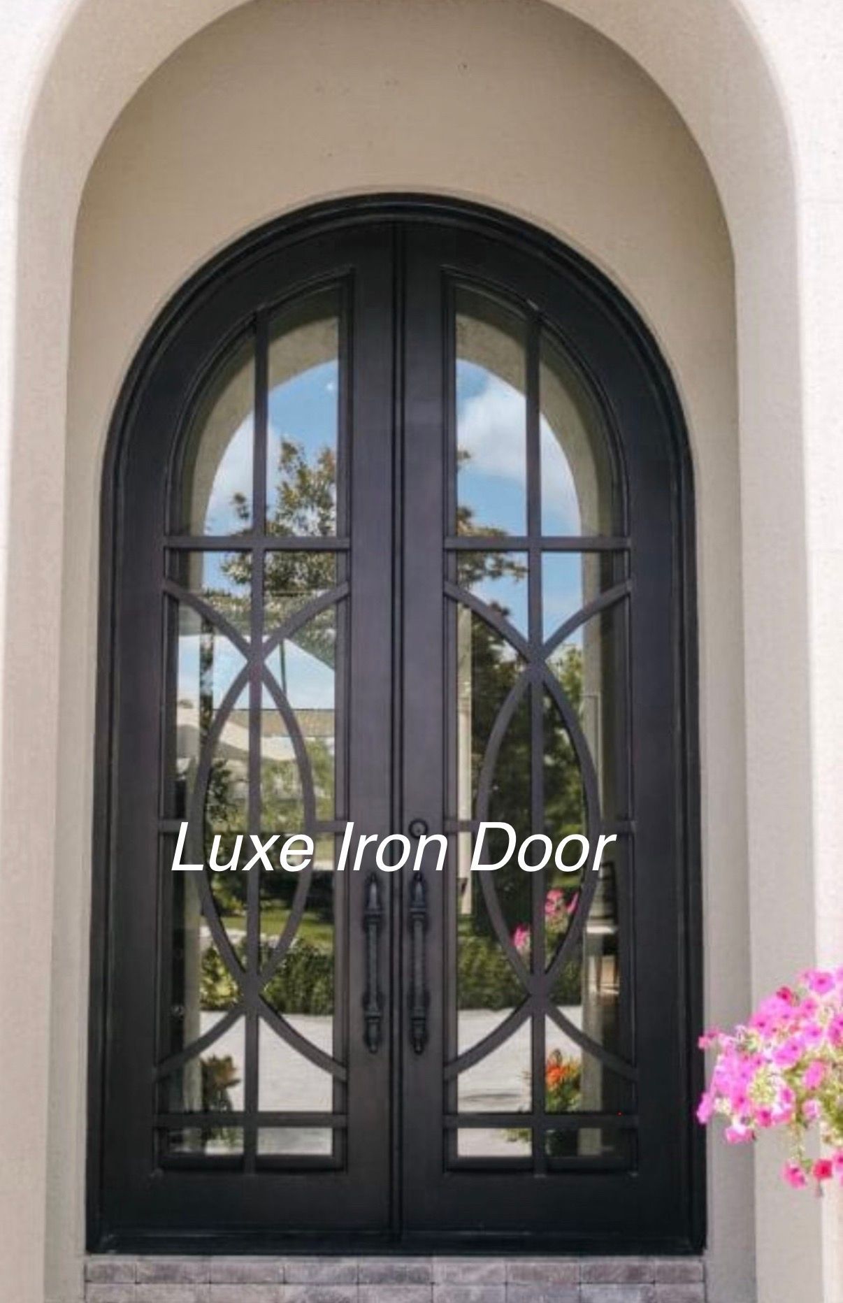 Black arched double front door with glass panels and decorative wrought iron in a stucco entryway