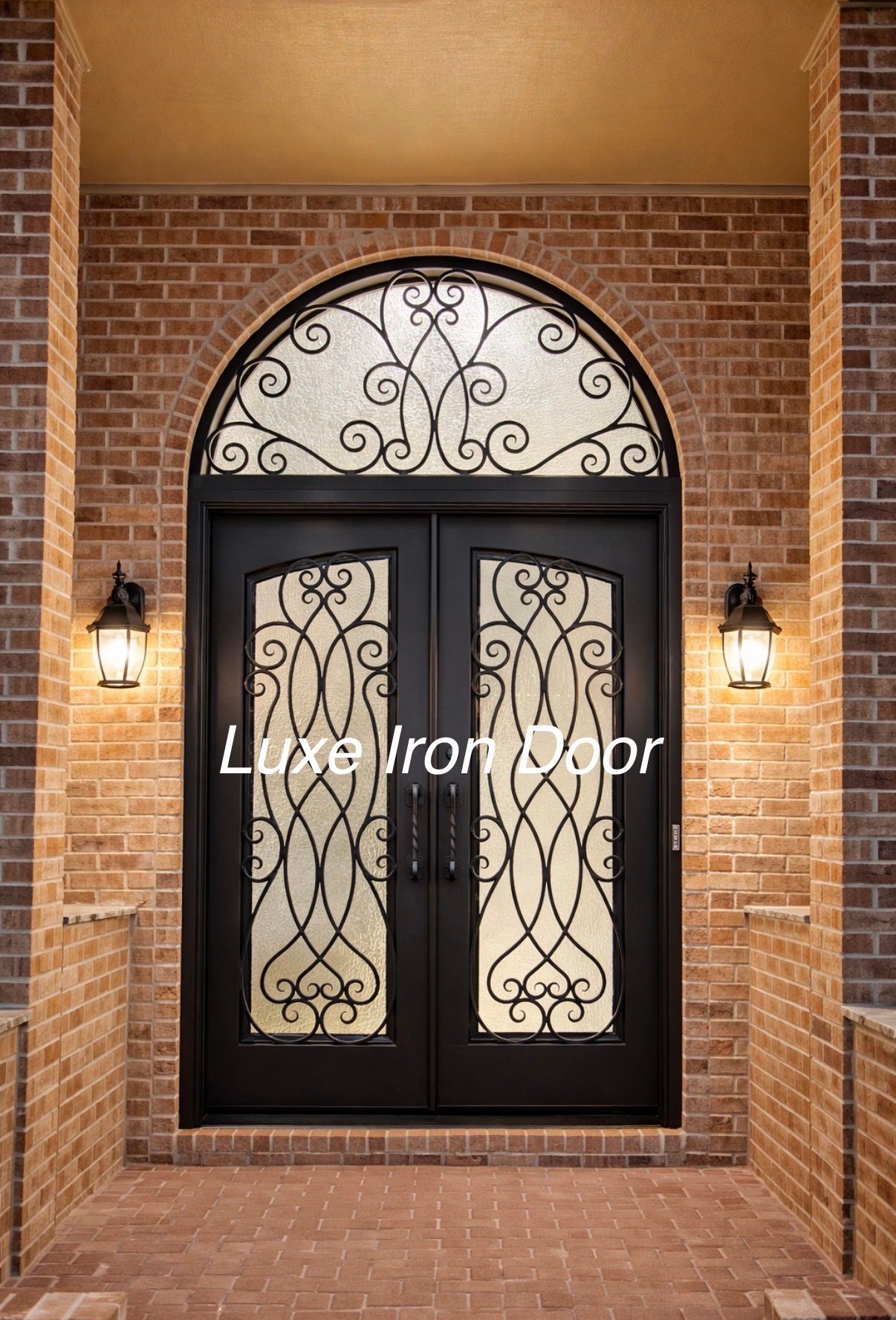 Black iron double front door with decorative glass and brick archway at a home entrance