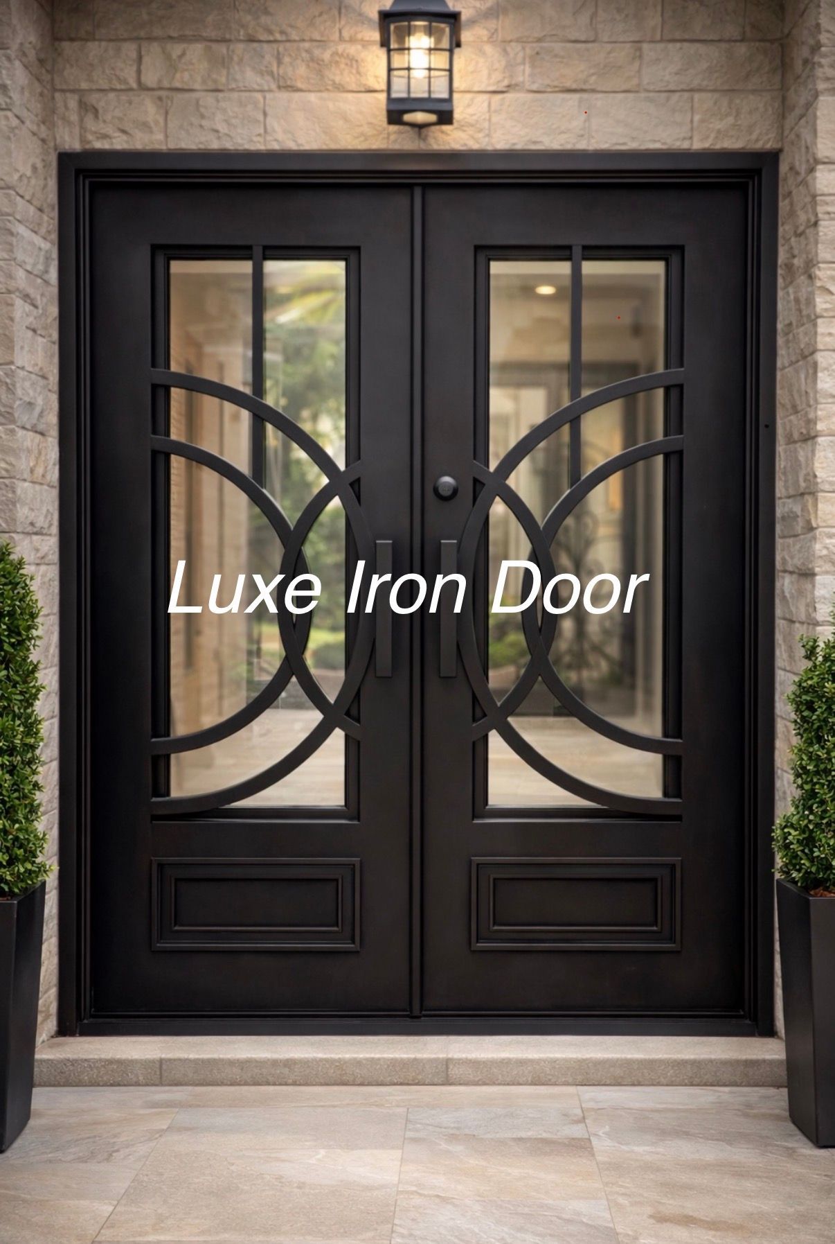 Black iron double front doors with glass panels and decorative curves beneath a wall lantern