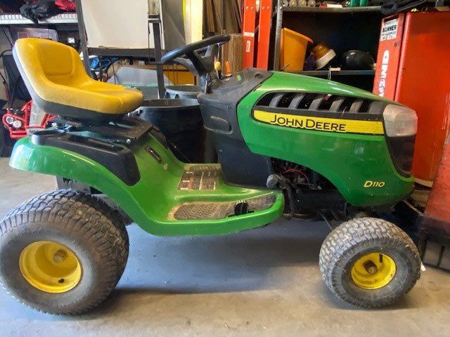 A john deere lawn mower is parked in a garage