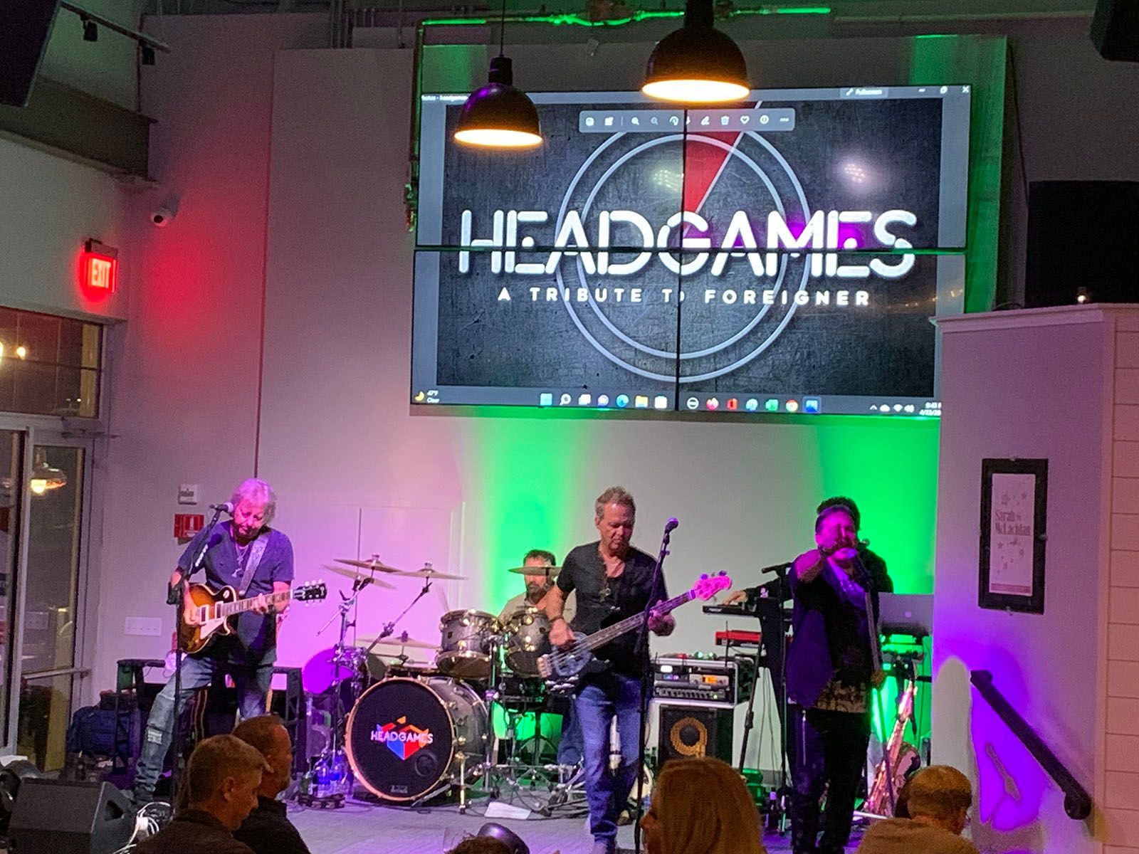 A group of men are playing instruments on a stage in front of a large screen