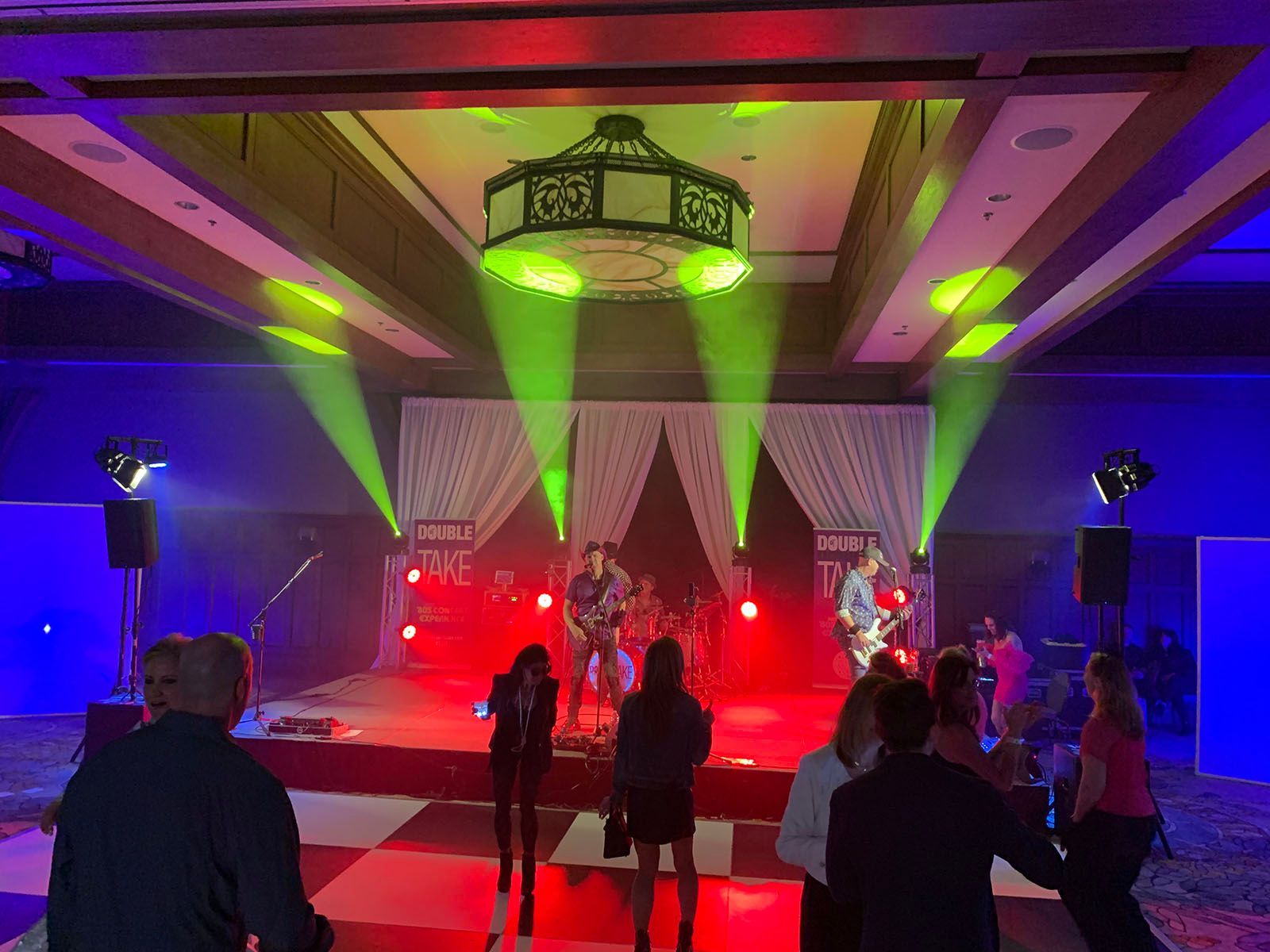 A group of people are standing in front of a stage with a band on it