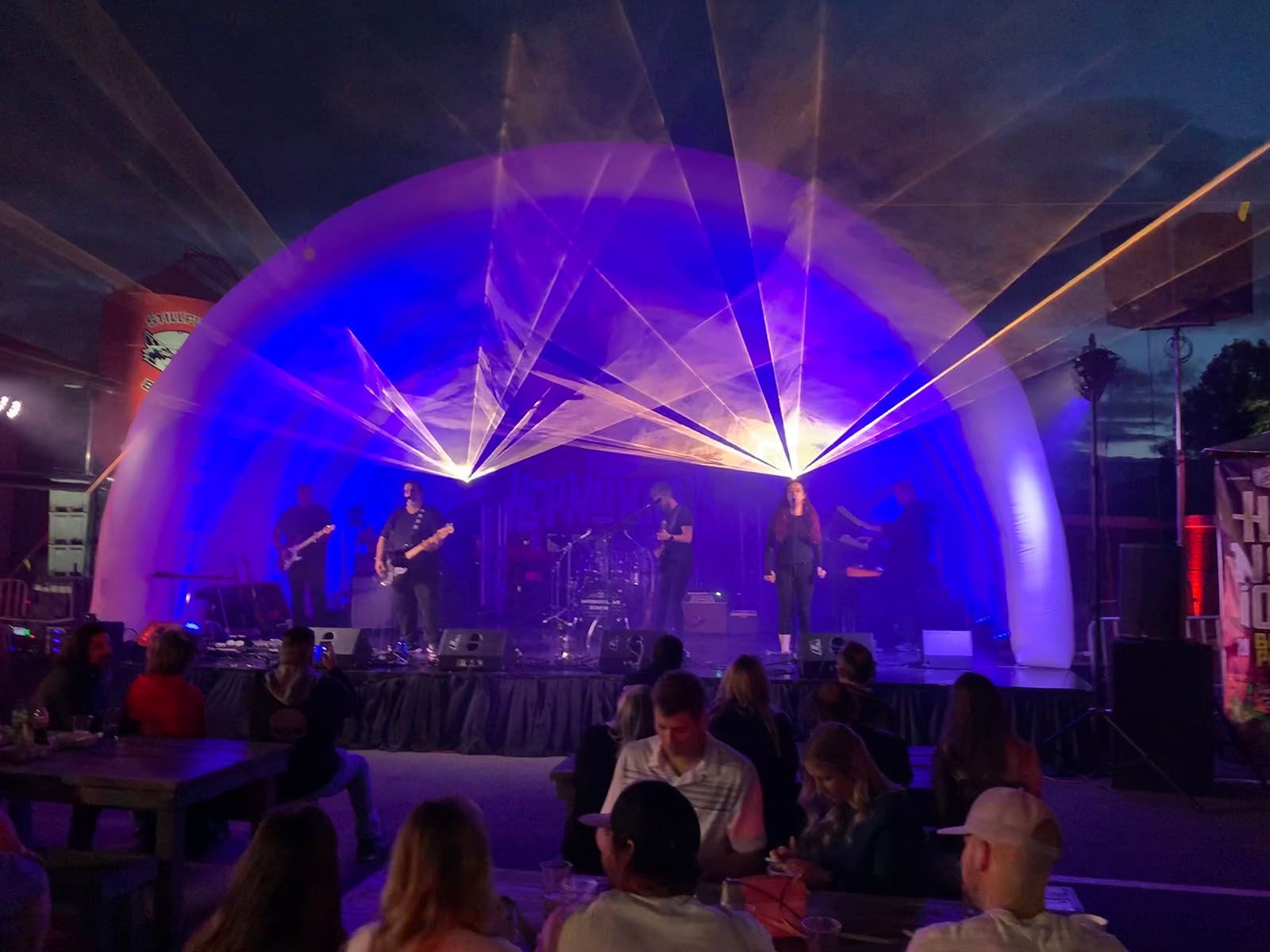 A group of people are sitting in front of a stage with a band on it