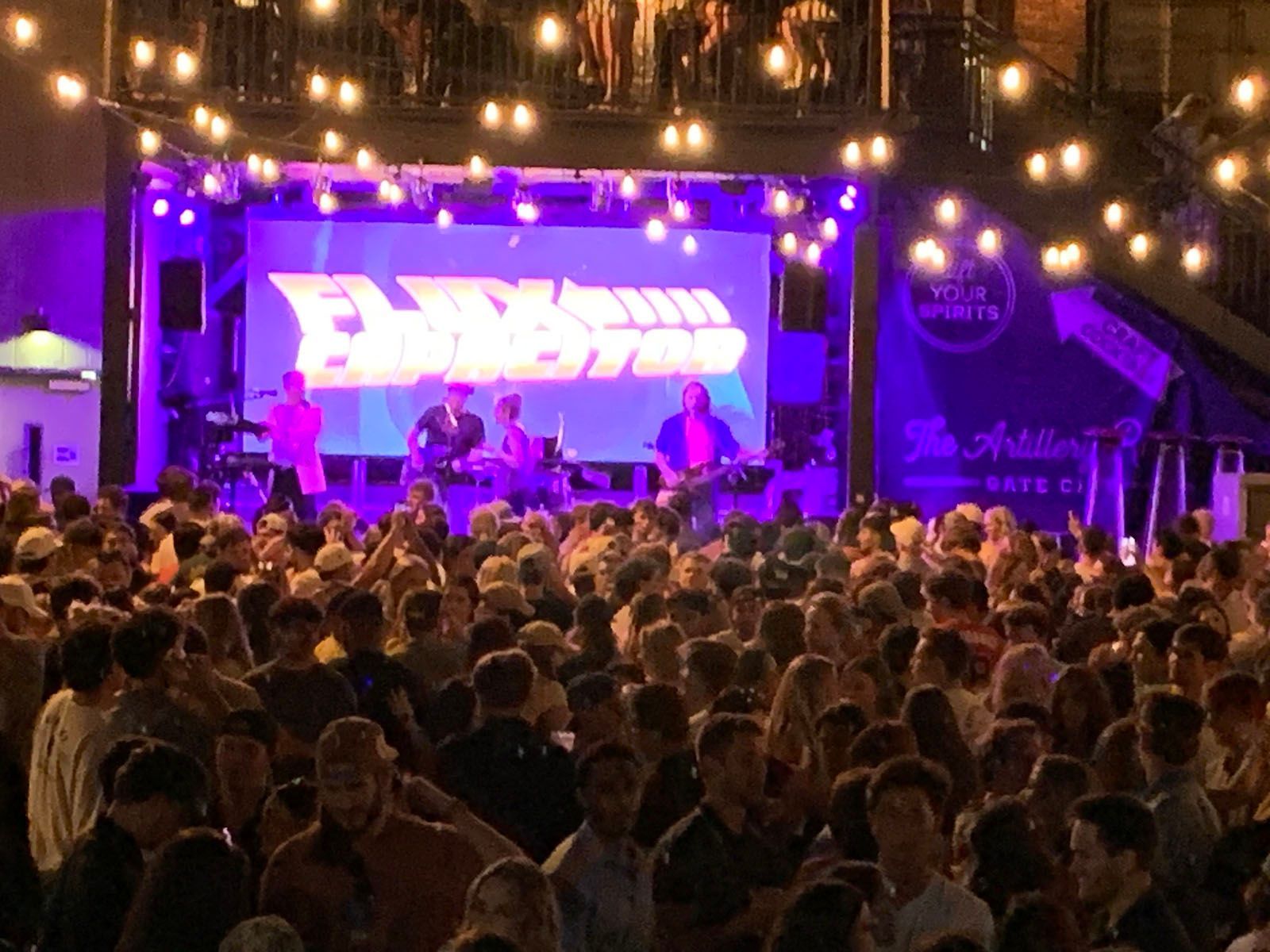 A large crowd of people are sitting in front of a stage at a concert