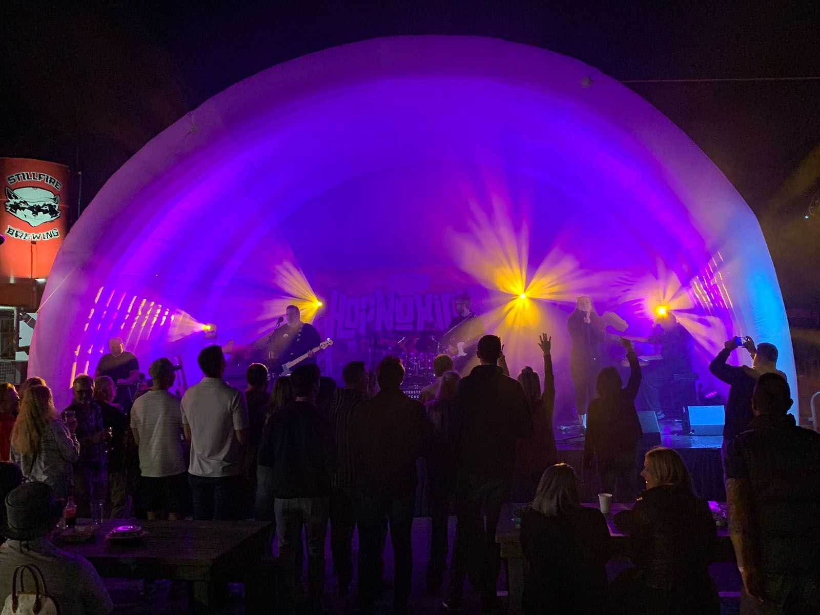 A group of people are standing in front of a stage with purple lights