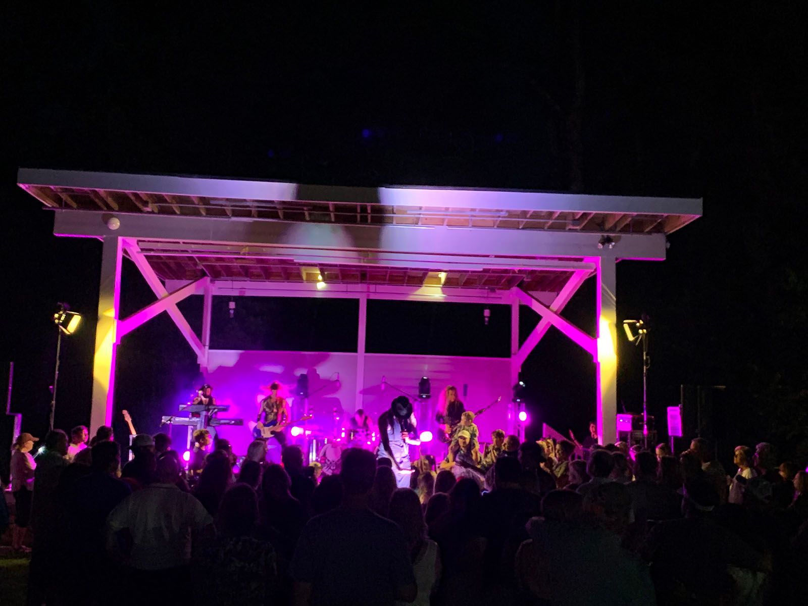 A group of people are standing in front of a stage with purple lights