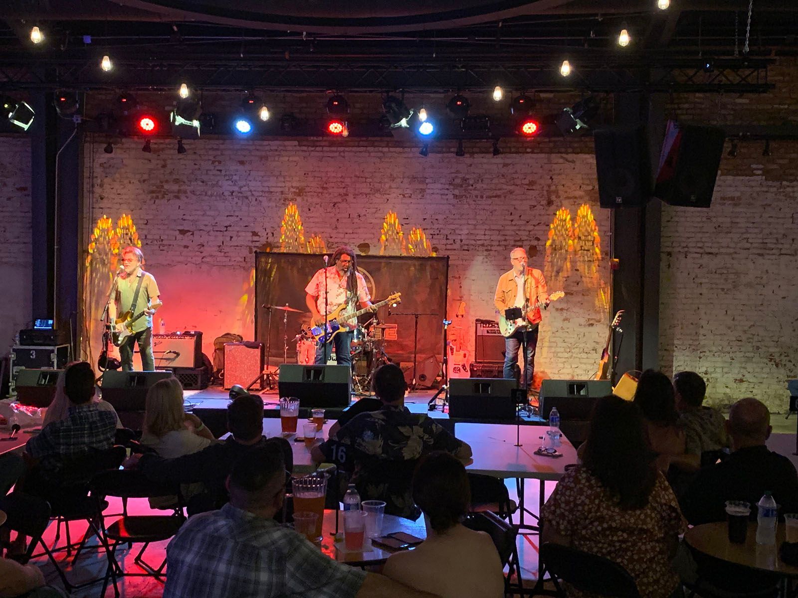 A group of people are sitting at tables in front of a stage with a band on it