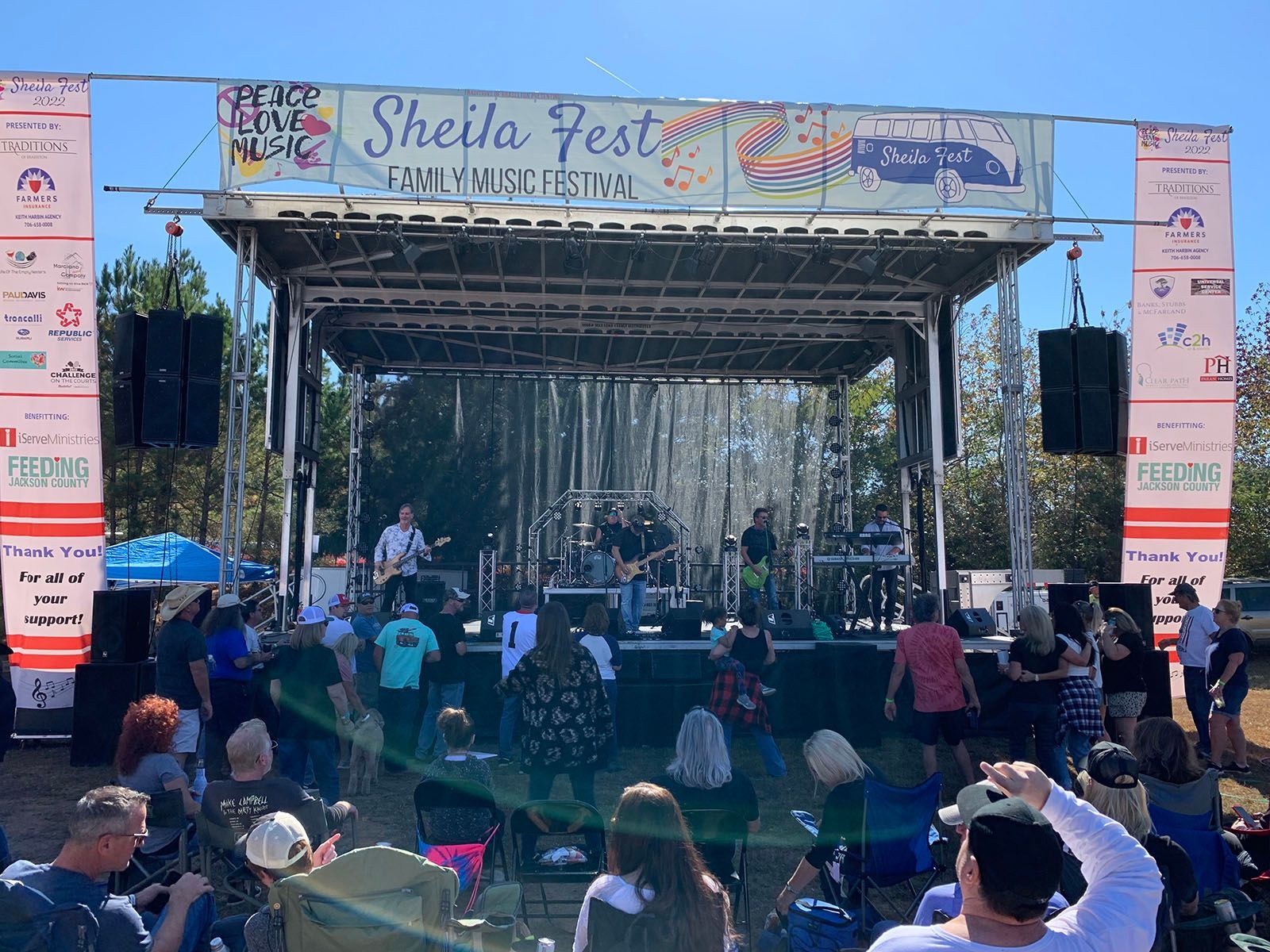 A group of people are standing in front of a stage at a festival