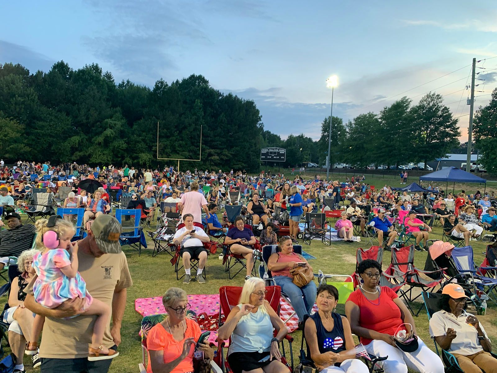 A crowd of people are sitting in chairs in a park