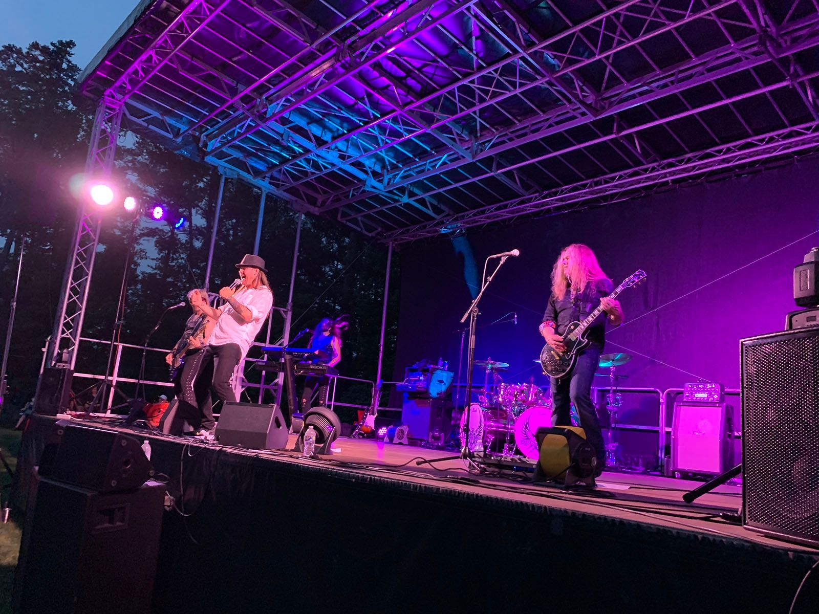 A group of people are playing instruments on a stage with purple lights