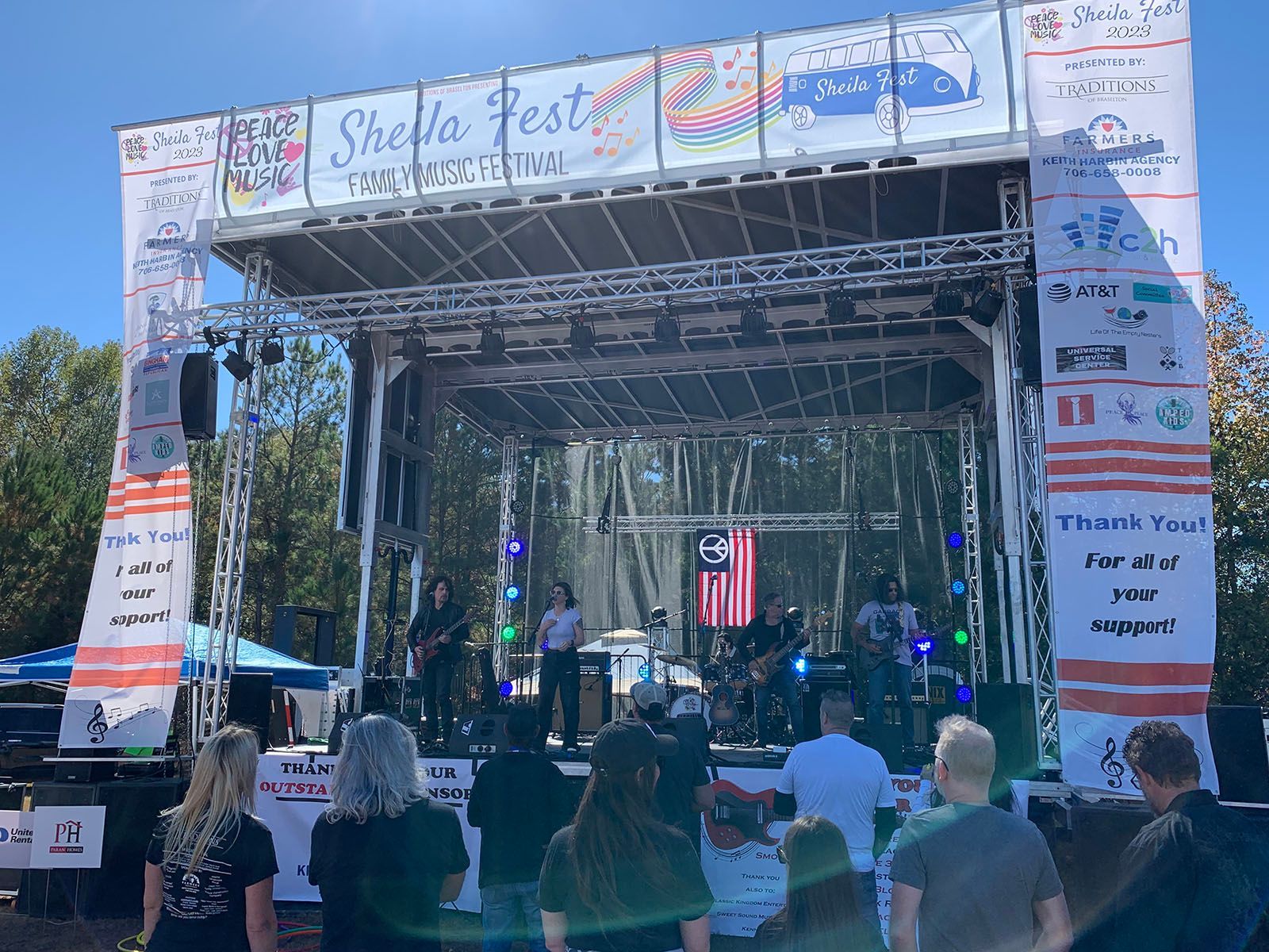 A group of people are standing in front of a stage at a festival