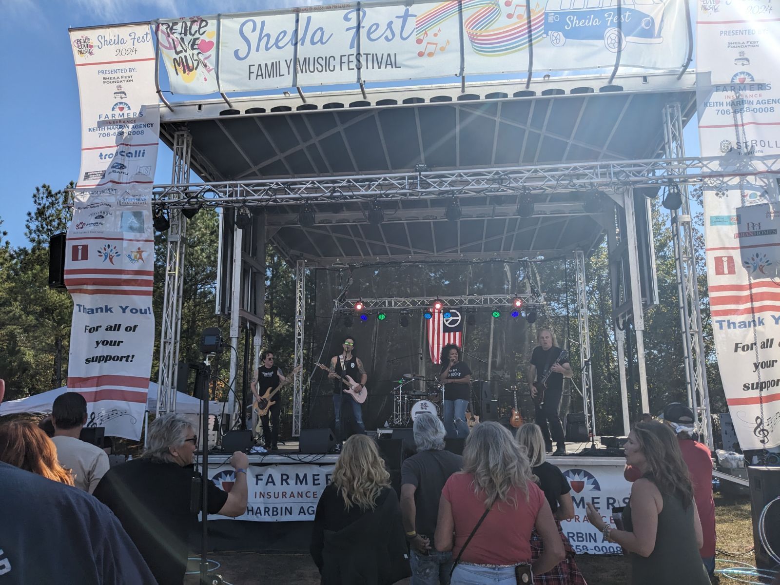 A group of people are standing in front of a stage at a festival