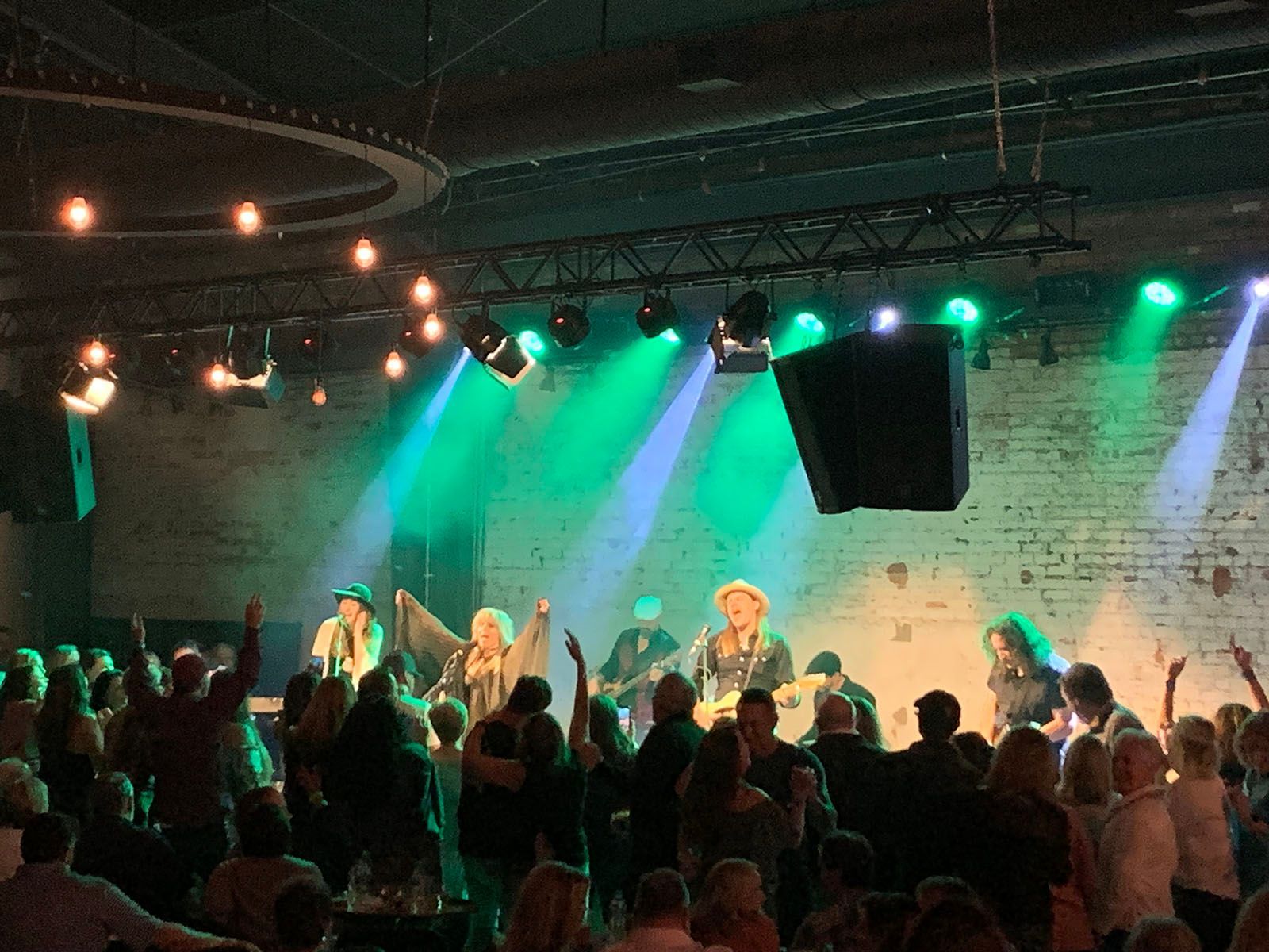 A group of people are dancing in front of a stage with green lights