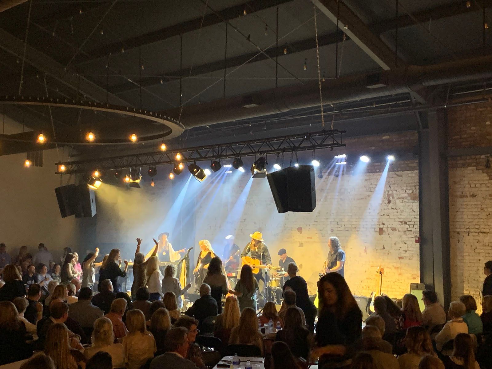 A group of people are standing in front of a stage in a large room