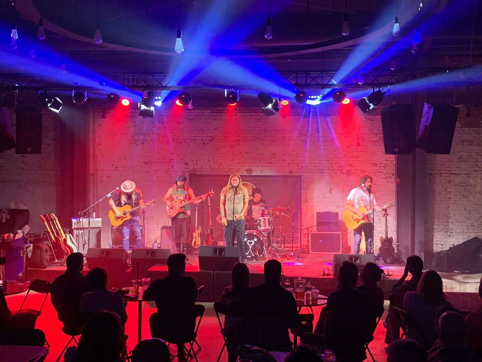 A crowd sitting in front of a stage with a band on it