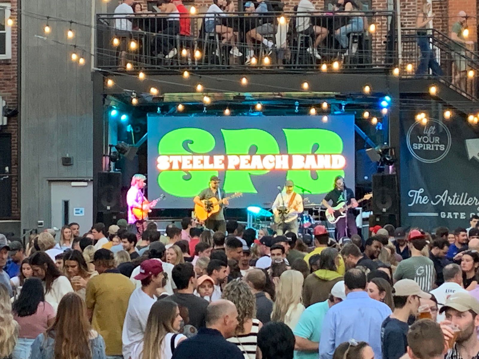 A large crowd of people are watching a band perform on stage