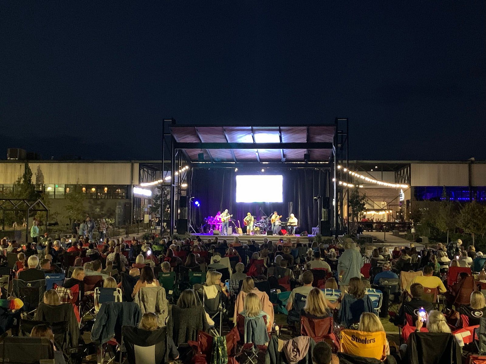 A crowd of people are sitting in front of a stage at a concert