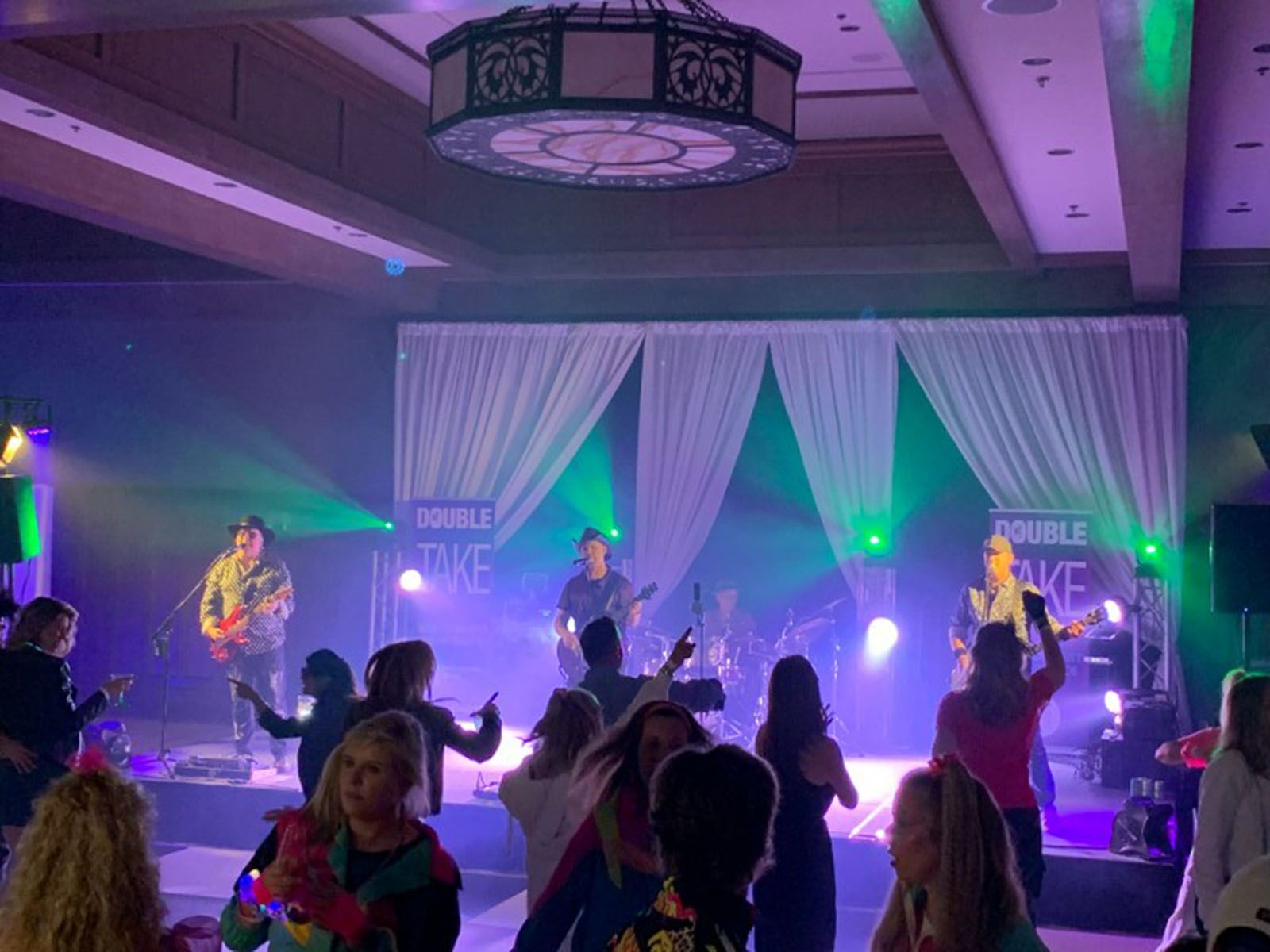 A group of people are dancing in a large room at a concert