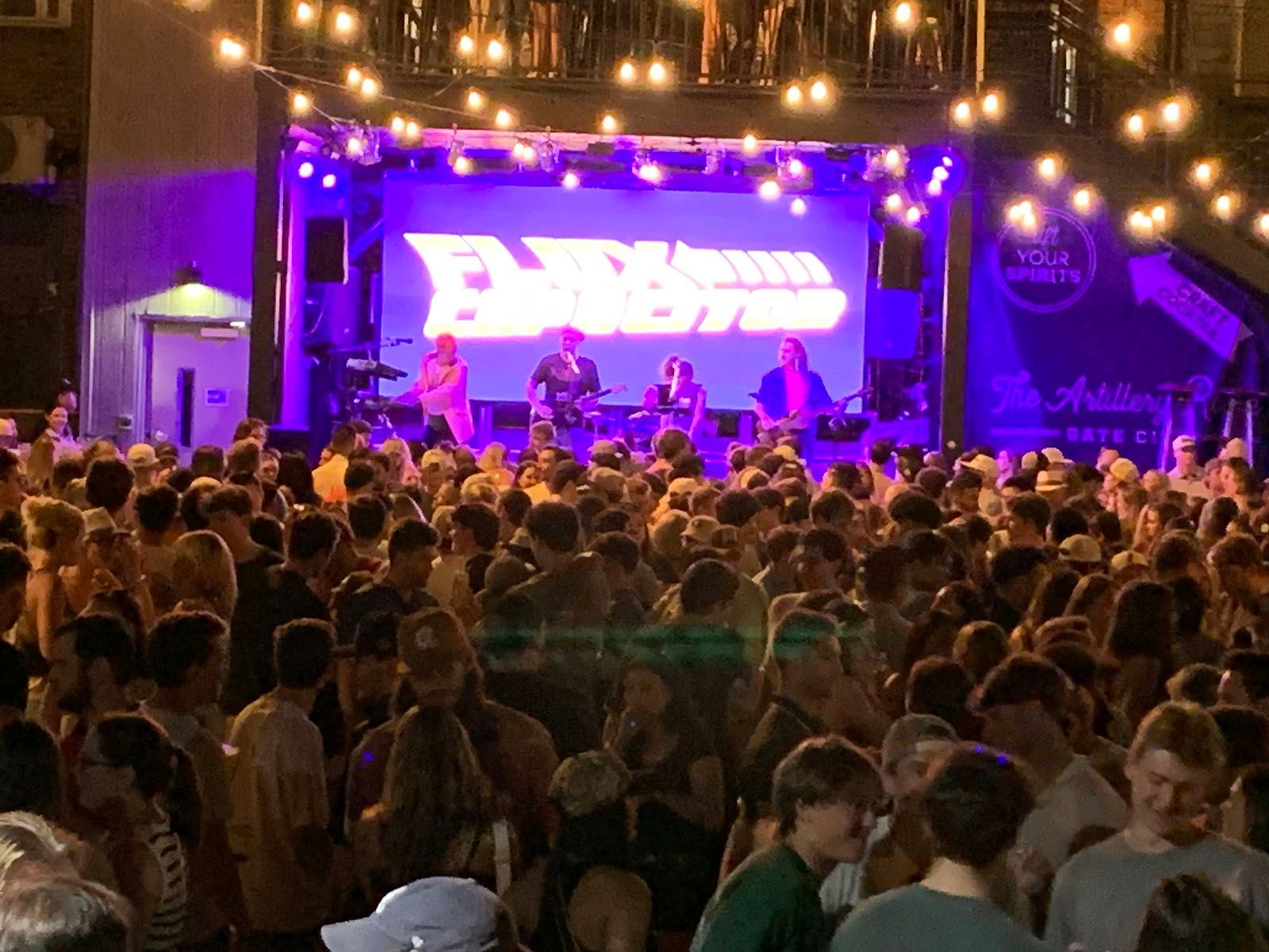 A crowd of people are gathered in front of a stage at a concert