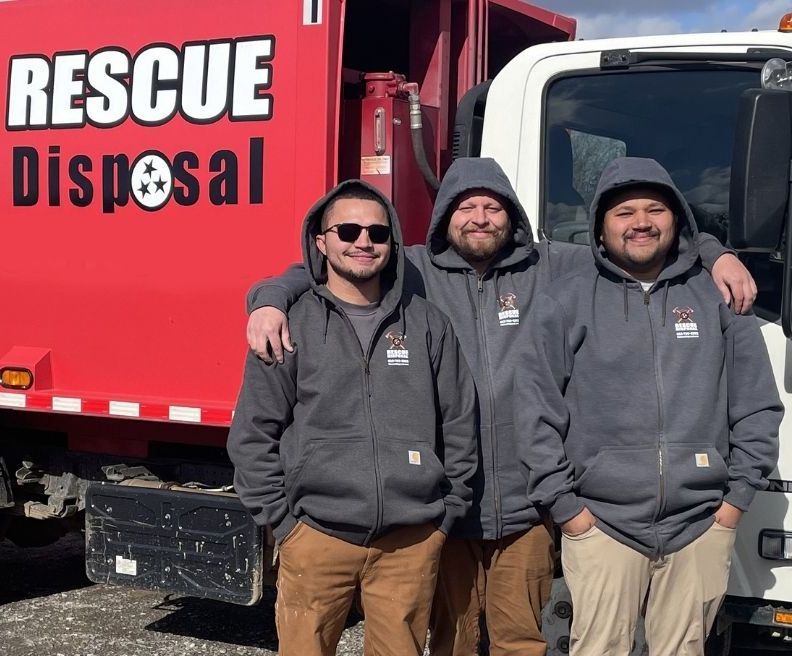 Three workers in gray hoodies stand beside a red Rescue Disposal truck.