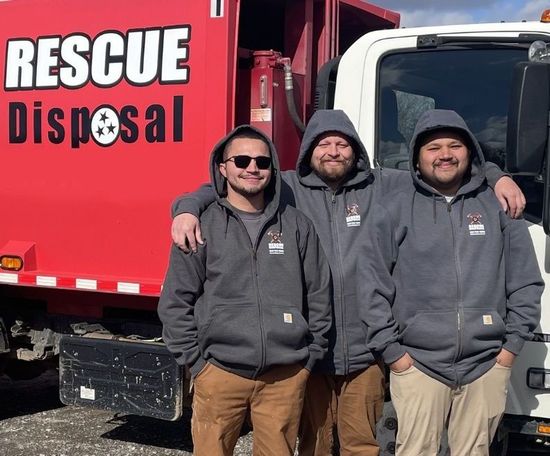 Three workers in gray hoodies stand beside a red Rescue Disposal truck.